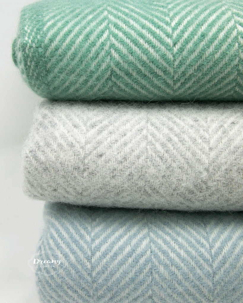 close up shot of folded wool blankets in teal green, grey, and soft blue colours - dreamylondon